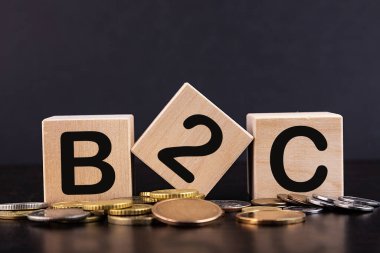 B2C harfli üç tahta küp madeni paralarla siyah masada müşteriye iş demektir.