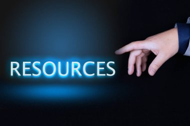 RESOURCES metin, siyah arkaplan üzerinde neon harflerle yazılmış kelime bir kişinin işaret parmağı ile bir el tarafından gösterilir.
