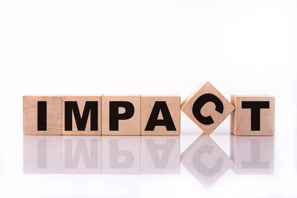 IMPACT word, text written on wooden cubes on a white background with reflection.