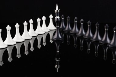 Yansıtıcı yüzeyde siyah ve beyaz satranç taşları. İş konsepti. Oyun, strateji, bilgelik, kararlılık.