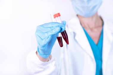 Bilim, kimya, biyoloji, tıp ve insan konsepti - klinik laboratuarında araştırma yapan, kan örneğiyle test tüpü tutan genç kadın bilim adamına yakın çekim