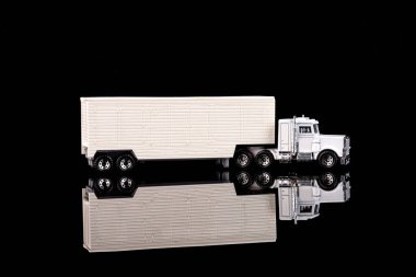 Oyuncak Amerikan beyaz kargo kamyonu siyah yansıtıcı arka planda.