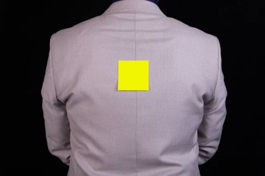 İşadamı sırtında bir çıkartmayla ayakta duruyor ve mesaj yazıyor. İş konsepti, sansür.