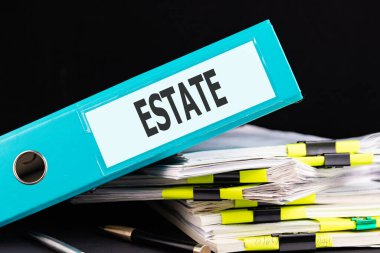 Metin Gayrimenkul, masadaki kağıt yığınının üzerinde duran bir klasöre yazılır. İş konsepti