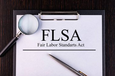 FLSA metni, masanın üzerinde duran bir kalem ve büyüteçle bir deftere yazılır. İş konsepti.