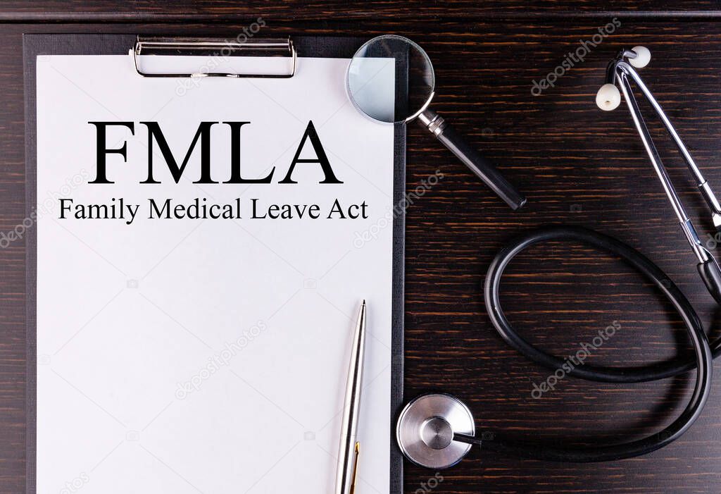 FMLA text is written on a tablet lying on a dark table with a stethoscope and a magnifying glass. Medical concept.