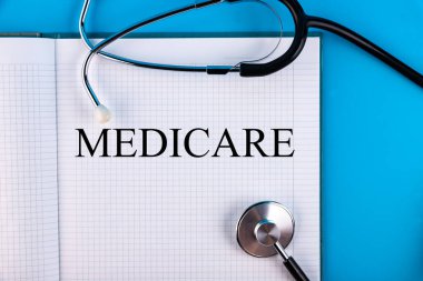 Masanın üzerinde duran bir not defterine ve steteskopa yazılmış tıbbi bakım metni. Tıbbi konsept.