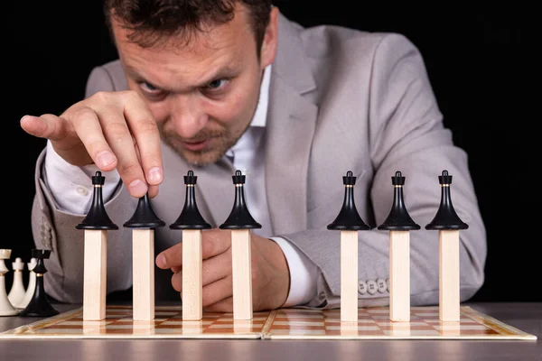 A businessman is building a pyramid of chess pieces and wooden blocks. The concept of construction, growth, development, success.