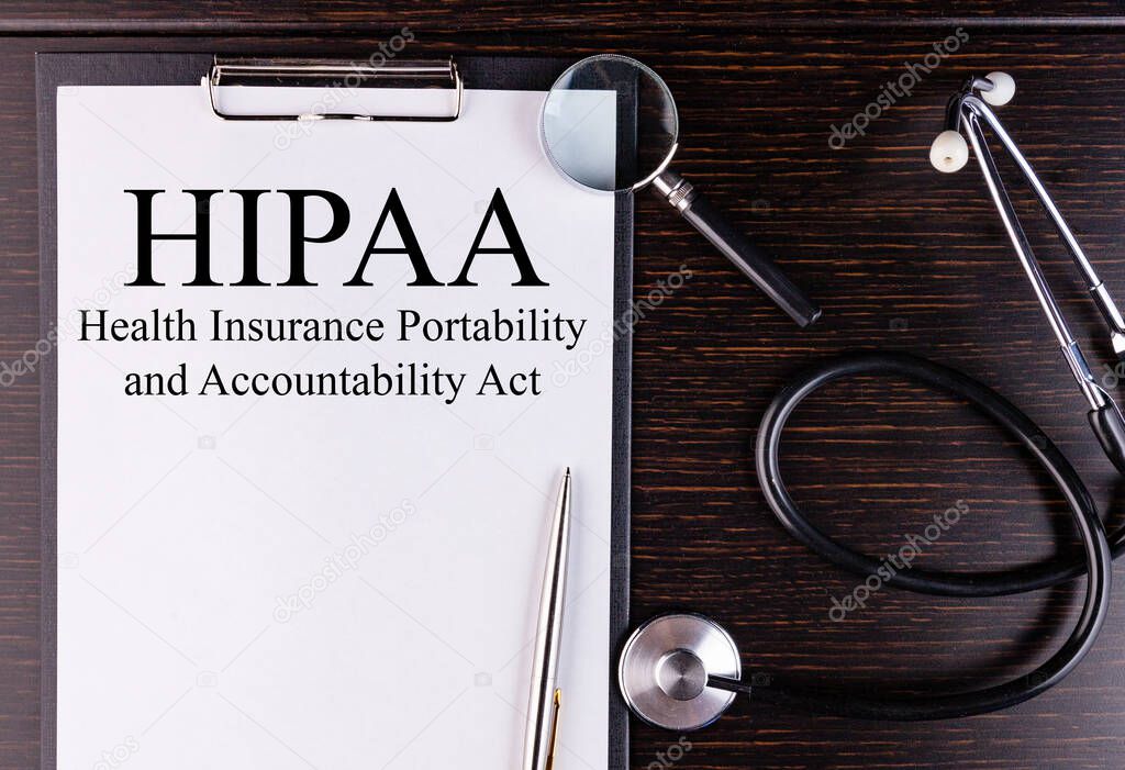 HIPAA text is written on a tablet lying on a dark table with a stethoscope and a magnifying glass. Medical concept.