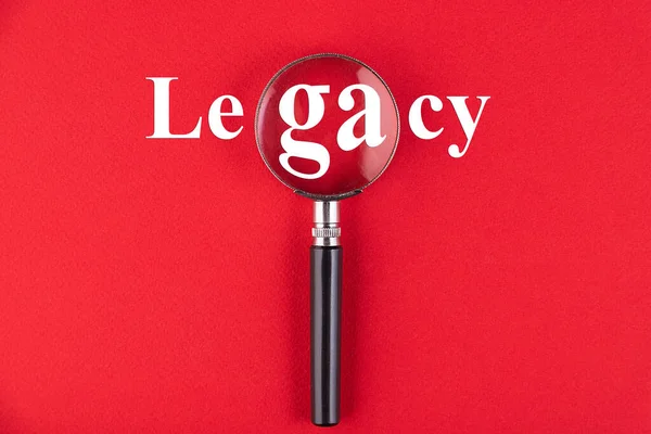 Legacy Tekst Geschreven Door Een Vergrootglas Een Rode Achtergrond Bedrijfsonderwijsconcept — Stockfoto