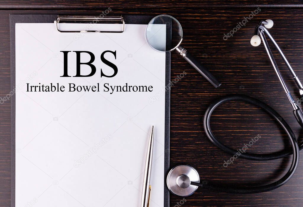 IBS text written in a notebook lying on a desk and a stethoscope. Medical concept.
