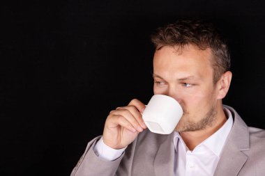 Yüzünde duygu olan bir iş adamı kahve içiyor. Behnes kavramı.