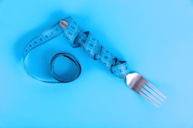 Diyet, zayıflatma konsepti, çatallı şerit ve mavi arka plan. Sağlıklı gıda konsepti.