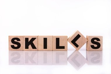 SKILLS kelime, metin, ahşap küplere, yapı taşlarına, beyaz arkaplan üzerinde yansıma ile yazılmış.