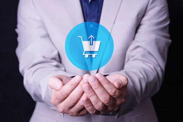 A man, a businessman holds a shopping basket logo in his palms. Supermarket cart icon on virtual screen. Retail trade Online retail store.