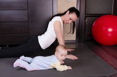 Oğluyla birlikte genç ve güzel bir anne spor, yoga, egzersiz ve beden eğitimine gider. Doğumdan sonra fiziksel iyileşme kavramı.