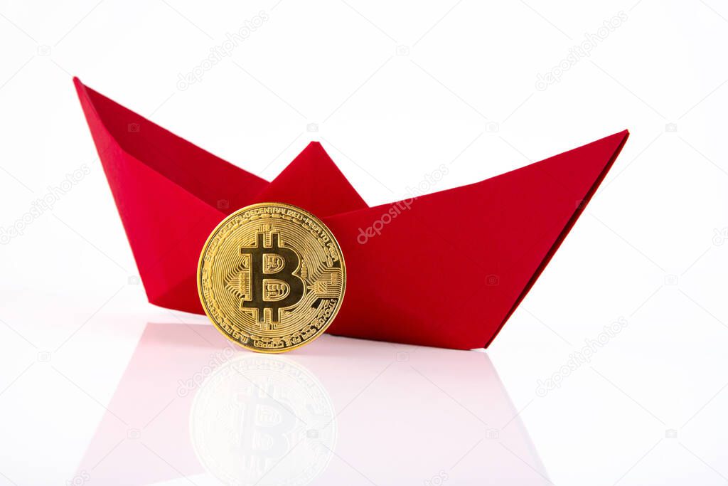 Red paper ship, golden bitcoin isolated on white background. Copy space.