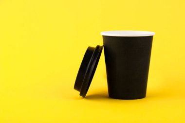 Eko siyah kağıt bardak, sarı arka planda kahve kağıdı fincanı. Reklamınız için maket yapın. Boşluğu kopyala.