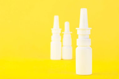 Tıbbi burun spreyi, beyaz plastik tıbbi ambalaj, sarı arka planda izole edilmiş konteynır. Boşluğu kopyala