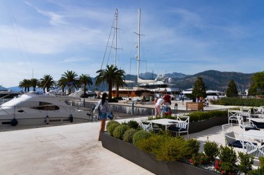 Tivat, Karadağ - 20 Ekim 2020 Limanda turist bir kız yürüyüş yapıyor ve motorlu tekne ve yat manzaralı.