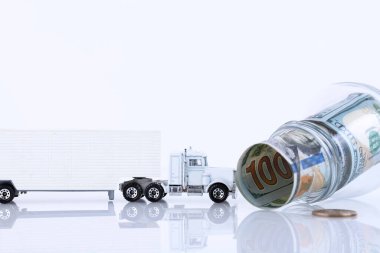 100 dolarlık banknotlarla dolu cam kavanoz ve beyaza izole edilmiş bir kamyon. Boşluğu kopyala.