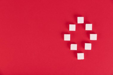 Kırmızı zemin üzerinde beyaz şeker küpleri sıfırıncı sırada. Boşluğu kopyala.