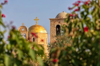 Bulanık bitkilerin arasından çan kulesinin ve Hıristiyan kilisesinin altın kubbelerinin manzarası