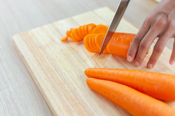 Fresh carrot and cut pieces on wooden cutting board