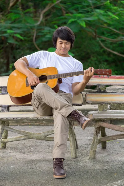 The guy playing the guitar, outdoor, cargo pants.