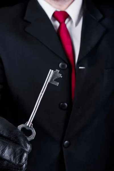 Man in black with a key — Stock Photo, Image