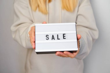 Üzerinde yazı olan bir kutu. Bir kızın elinde satılık. Sezon indirimi, tatil alışverişi. Tüketiciler için özel teklif. İndirimli reklam promosyonu. Ürün ve hizmetlerin pazarlama tanıtımı