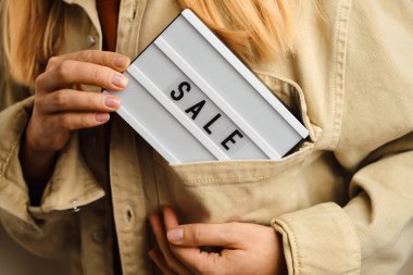 Üzerinde yazı olan bir kutu. Bir kızın elinde satılık. Sezon indirimi, tatil alışverişi. Tüketiciler için özel teklif. İndirimli reklam promosyonu. Ürün ve hizmetlerin pazarlama tanıtımı