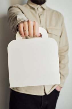 Bir adam elinde tutacağı olan bir karton kutu tutuyor. Mallar için ambalaj ve hediye. Posta ve teslimat servisi. Hediye kutusu kapanıyor. Karton kutu. Tasarım, harf ya da reklam için boş alan modeli