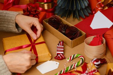 Noel hediyelerini paketleyen kadın. Mutlu bayramlar. Hediyelerle dolu bir kutu. Boks günü, Noel ve yeni yıl partisi için sürpriz. Sihir zamanı. Kış kutlamaları. Paket kağıdı, oyuncaklar ve kurdele