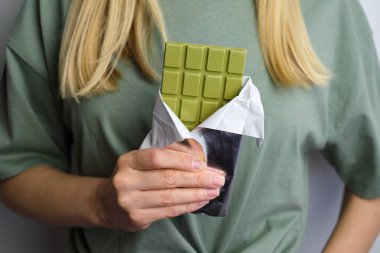 Bir kızın elinde kibritli çikolata. Yeşil çikolata çubuğu. Lezzetli tatlı. Kakao ve Japon yeşil çay şekeri. Sağlıklı vejetaryen yemeği. Organik yiyecekler. Çikolata yakın plan.