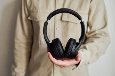 Kablosuz siyah kulaklıklar bir adamın elinde. Meloman için modern bir ses cihazı. Müzik, podcast, rahatlama ve dinlenme dinleyelim. Taşınabilir konforlu stereo cihaz. Akıllı kablosuz teknoloji 
