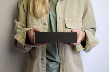 Elinde küçük siyah bir karton kutu tutan bir kadın. Yeni paketi olan genç bir kız. Kutu kapanıyor. Tatil hediyelerini açma zamanı. Posta servisi, teslimat. El işi kağıdı. Hediye kutusu, hediye. Kutu kutusu