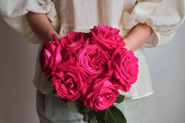 Pink roses in the hands of a happy woman. Rose petal close-up. Beautiful holiday spring bouquet. Florist girl with blossom flower. Fresh floral bunch. Romantic surprise from a loved one