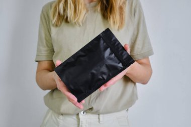 Kraft siyah kağıt ambalajı bir kadının ellerinde. Kahve ve kozmetik için ambalaj. Toparlanıyoruz. Satılık ürünler. İnternetten alışveriş. Sürpriz dolu kutular. Teslimat servisi, nakliye. Boş, model.