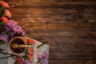 Ballı şeker, ahşap bir kavanozun içinde, kumaş ve ahşap bir masanın üzerinde çiçekler. Üst görünüm