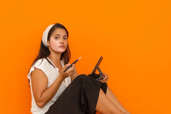 Güzel Latin kadın güzellik tedavisi yapıyor. Güzellik maskesi takarken kameraya bakan bir kadın.