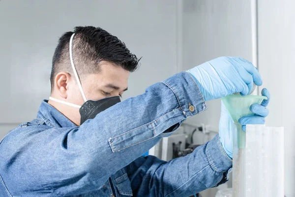 Yüz koruma maskesi ve mavi lateks eldivenli sanayi işçisi jeoloji laboratuvarında testler yapıyor.