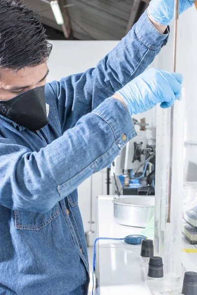 Yüz koruma maskesi ve mavi lateks eldivenli endüstriyel işçiler jeoloji veya bilimsel laboratuarda testler yaparlar.