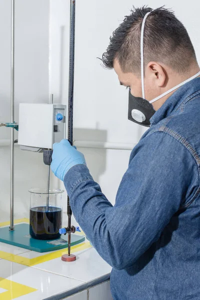 Jeoloji laboratuarında yüz koruma maskesi ve mavi lateks eldivenli sanayi işçisi.