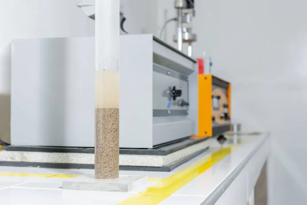 Jeoloji laboratuvarı ekipmanları. Odaklı kumu ve suyu olan büyük bir pipet ve arka planda endüstriyel ekipman