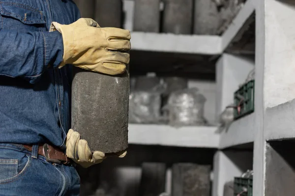 Erkek endüstriyel işçilerin ellerini koruyucu eldivenlerle kapatın. Ellerinde beton bir silindir var.