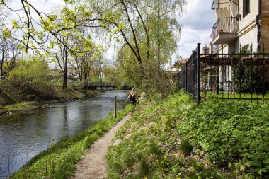 Vilnius, Litvanya - 21 Nisan 2025Uzun saçlı genç bir kız Vilnius 'un sanatsal Uzupis bölgesinde Vilnius nehri boyunca yürüyor..