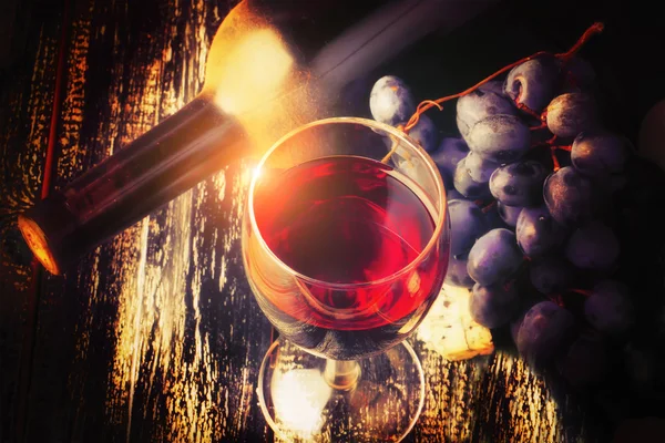 red wine and grapes on an old shabby wooden background bottle of dusty retro rustic style