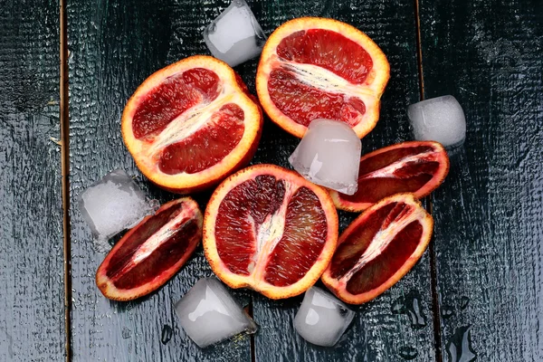 Красный сочный апельсины со льдом на темном деревянном фоне для летнего освежающего напитка — стоковое фото