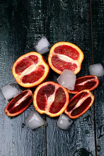 Красный сочный апельсины со льдом на темном деревянном фоне для летнего освежающего напитка — стоковое фото